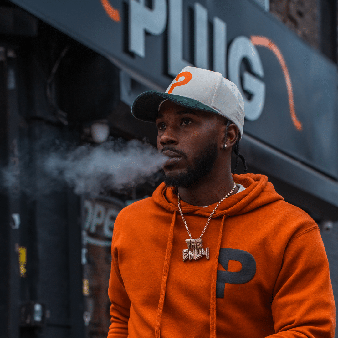 Man smoking wearing The Plug merch